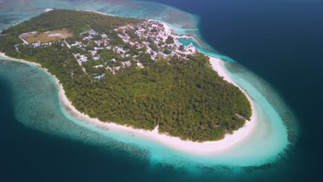 Blick-Von-Oben-Auf-Eine-Stadt-Auf-Einer-Maledivischen-Insel-Inmitten-Dichter-Grüner-Bäume,-Die-Auf-Allen-Seiten-Von-Herrlichem-Blauem-Wasser-Umgeben-Sind