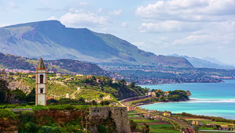 Time-lapse-shot-of-rural-coastline-of-Sicily-and-church-during-sunny-day---Beautiful-mountain-range-in-background---View-from-Belvedere-Termini-Imerese,Italy