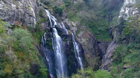 Aerial-Rising-Behind-Tree-To-Reveal-Fervenza-do-Toxa-Waterfalls-Cascading-Down-Rockface