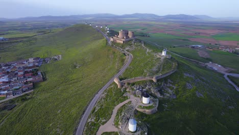 Aerial-top-view-of-ancient-windmills-and-medieval-fortress-hill-top-above-Consuegra-town,-Spain