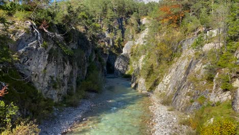 Rocky-canyon-with-Karwendelbach-river-in-the-near-of-Scharnitz-in-Austria-with-trees-and-high-Karwendel-mountains-in-the-background