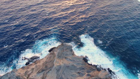 Aerial-view-of-ocean-waves-crashing-on-a-rocky-mountain