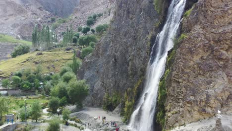 Luftdrohne-Schwenkt-Nach-Links-Am-Manthokha-Wasserfall-In-Skardu,-Pakistan,-Während-Touristen-Unten-Von-Bergen-Umgeben-Sind,-Die-An-Einem-Sonnigen-Sommertag-Fotos-Machen
