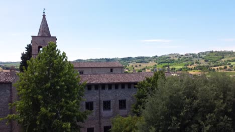 Revealing-a-little-Italian-town-behind-the-trees,-ascending-view