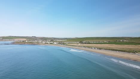 A-aerial-footage,-following-long-sandy-beach-with-gentile-waves-on-a-sunny-day-in-Ireland