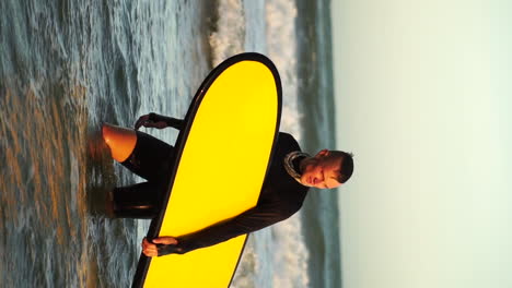 Guy-in-wetsuit-with-yellow-surfboard-is-returning-from-surfing-the-waves