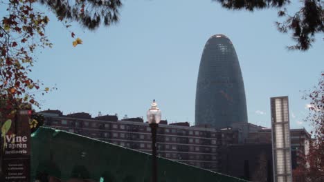 tower-glorifies-against-the-blue-sky-and-behind-the-buildings,-seen-from-El-Clot-park,-on-a-sunny-autumn-day-in-Barcelona