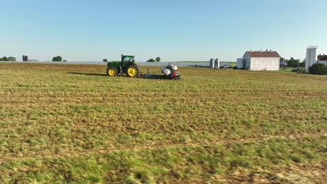 Low-aerial-orbit-around-John-Deere-tractor-pulling-planter-in-field