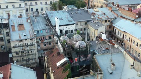 Aerial-drone-of-a-rooftop-bubble-restaurant-in-Lviv-Ukraine-surrounded-by-old-European-buildings