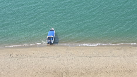 Small-Boat-Anchored-in-Sea-by-Sandy-Tropical-Beach,-High-Angle-View