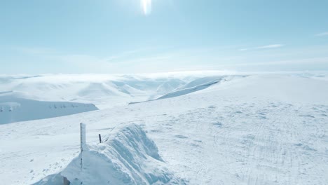 Vieja-Cabaña-Cubierta-De-Una-Gruesa-Capa-De-Nieve-En-La-Cima-De-La-Montaña-Svalbard,-Vista-Aérea