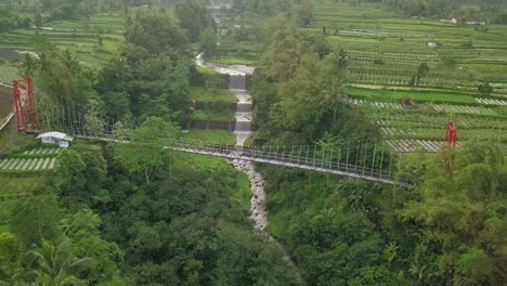 Aerial-drone-view-of-suspension-bridge,-valley-and-river-with-waterfalls