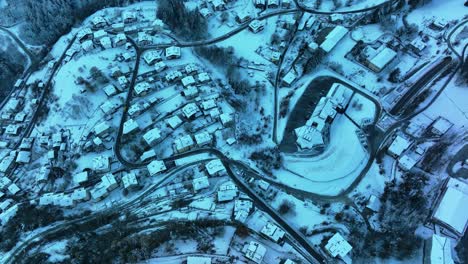 Vista-Aérea-De-Drones-Cenitales-De-Casas-Con-Nieve-En-Invierno-En-Un-Pequeño-Pueblo-En-Los-Alpes