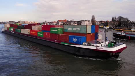 Aerial-Starboard-Tracking-Shot-Along-Salute-Cargo-Container-Ship-On-Oude-Maas