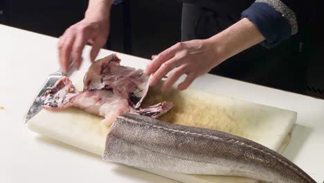 Chef-tearing-apart-peaces-of-fish-from-a-hake's-head-while-cleaning-it-up-in-a-Spanish-restaurant-in-Madrid