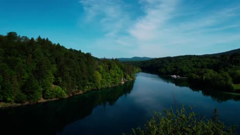 Plitvice-lakes-croatia,-drone-ascending-behind-trees,-revealing-emerald-green-lake