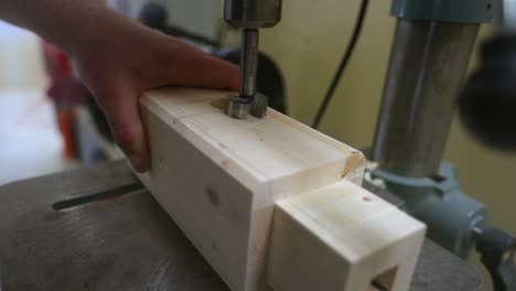 Drilling-out-a-tenon-slot-in-a-wood-beam-on-a-drill-press-in-slow-motion-as-wood-chips-are-displaced-in-every-direction