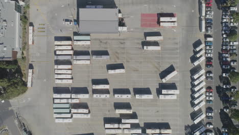 Bus-arriving-to-park-in-large-collect-of-vehicles-in-commercial-depot-as-seen-from-aerial-perspective-above