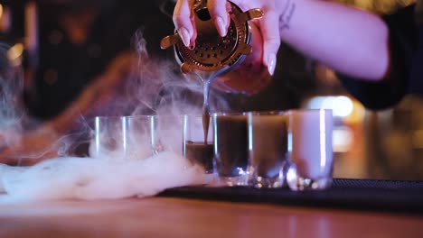 Barkeeper-Füllt-Trockeneis-Rauchende-Schnapsgläser-Mit-Buntem-Cocktail