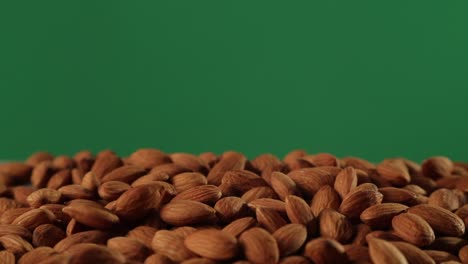 Almonds-falling-onto-almonds-against-green-screen