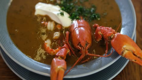 Fresh-healthy-seafood-soup-red-lobster-crayfish-served-with-smietana-and-parsley,-traditional-gourmet-food-dish