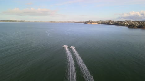 Flying-quickly-behind-2-jet-skis-along-the-coast-of-Orewa-beach-in-New-Zealand-at-sunset