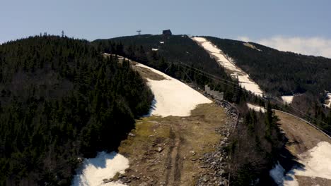 Ski-mountain-after-season-close-during-spring-with-melting-snow-and-historic-tram-building-Drone-Aerial-4k-30p