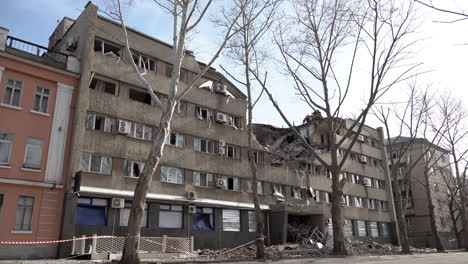 A-man-on-a-bicycle-cycles-past-a-hotel-that-was-hit-by-a-cruise-missile,-destroying-a-large-section-of-the-building-during-the-Russian-invasion-of-Ukraine
