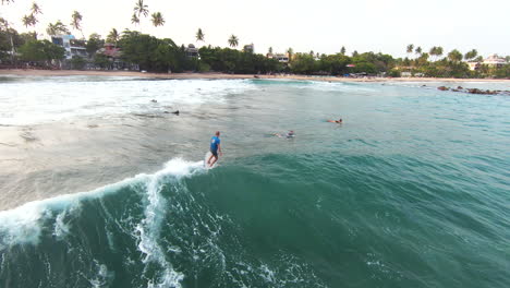 Tracking-Shot-Of-Surfers-Riding-Fast-Wave-In-Beautiful-Summer-Day,-Sri-Lanka