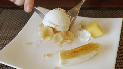 using-fork-to-eat-croffle-waffles-on-plate-with-ice-cream-and-caramel-banana