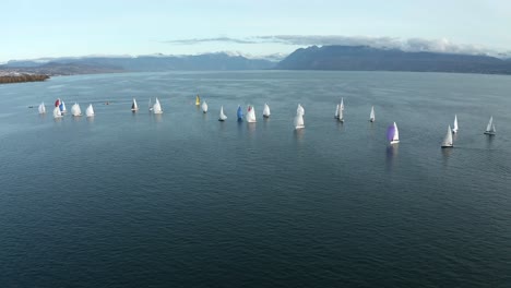 Wide-shot-pushing-in-on-a-multitude-of-yachts-sailing-on-Lake-Geneva-with-the-Swiss-alps-in-the-background