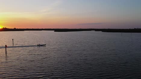 Aerial-view-around-a-boat-driving-across-the-sea,-sunset-on-the-coast-of-South-Florida---circling,-drone-shot