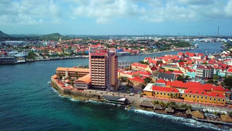 Aerial-view-truck-left-of-the-Punda-district-of-Willemstad,-Curacao-with-Otrobanda-and-the-Oil-Refinery-in-the-background
