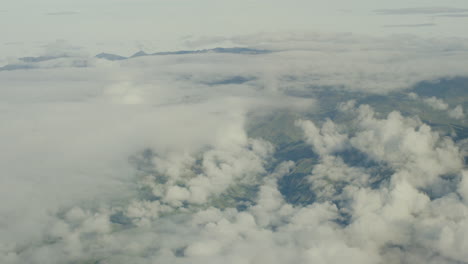 Vista-Aérea-Desde-El-Avión,-Las-Nubes-Y-Las-Montañas