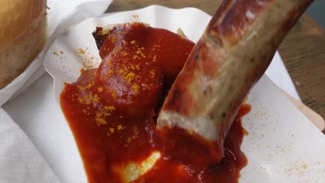Eating-large-currywurst-sausage-with-hand