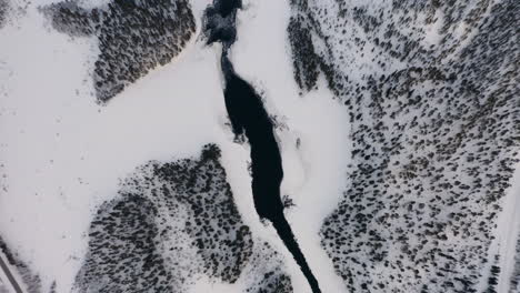 Aerial-view-looking-down-moving-down-over-cold-winter-woodland-lake-in-Norbotten-Swedish-landscape