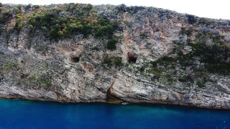 huge-sandstone-cliffs-with-holes-on-it-facing-the-blue-colored-sea