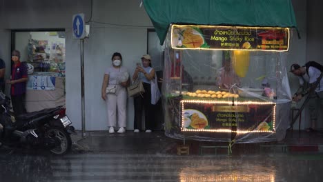 People-waiting-for-rain-to-stop-next-to-mango-sticky-rice-stall