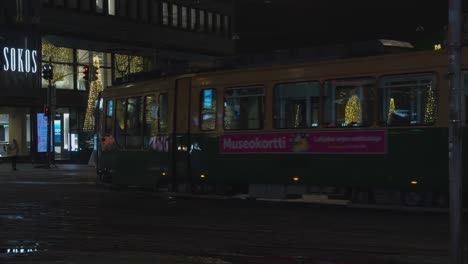 Electric-street-tram-rides-rails-past-festive-lights-in-Helsinki,-FIN