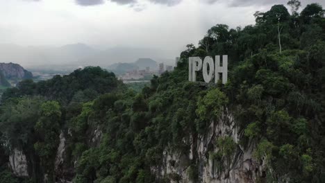 Aerial-panning-shot-around-the-sign-of-Ipoh-on-top-of-limestone-hill-at-Kawasan-Perindustrian-Tasek,-Perak-state,-Malaysia,-southeast-Asia