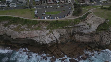 Maroubra-beach-neighborhood-houses-drone-zoom-in-close-to-the-car-park-with-ocean-view-at-sunset