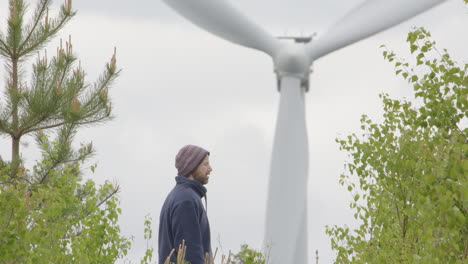 A-40-year-old-man-pauses-during-a-walk-to-look-at-the-huge-wind-turbine-in-front