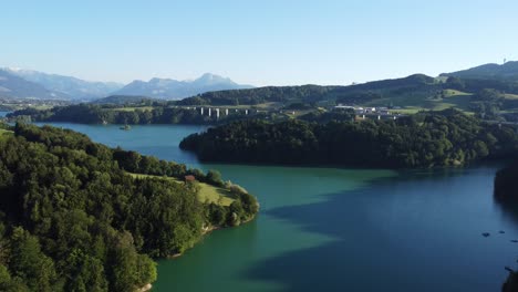 Blick-über-Den-Imposanten-Lac-De-Gruyere-Mit-Autobahnbrücke-Und-Den-Schweizer-Bergen-Im-Hintergrund,-Idyllisches-Licht-Am-Abend