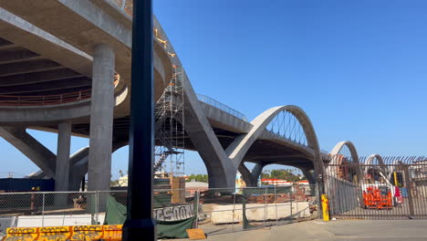 Arcos-Del-Puente-Del-Viaducto-De-La-Sexta-Calle-En-Los-ángeles,-Panoramización-Hacia-Abajo-Para-Revelar-Un-Scooter-De-Pájaro-En-La-Acera