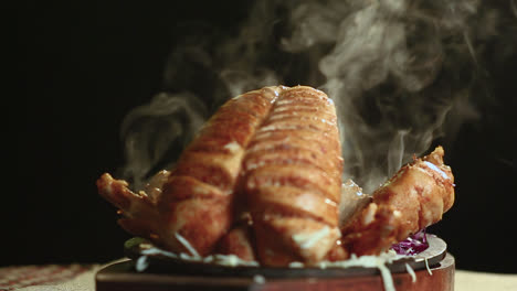 Close-Up-Of-Roasted-Chicken-Bbq-on-Round-Table-With-Smoke-Black-Background