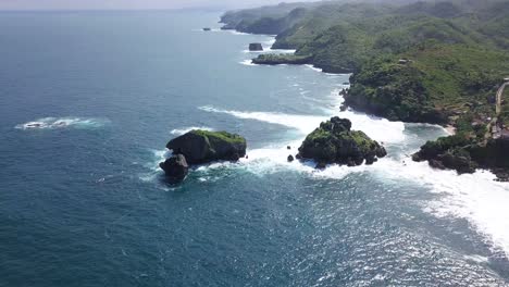 Aerial-view-from-above-of-giant-ocean-waves-crashing-and-foaming-big-rock-stones