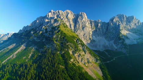Stunning-aerial-view-across-woodland-covered-slopes-of-sunlit-Wilder-Kaiser-mountains-peaks