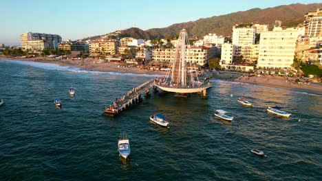 tourists-and-boats-at-Muelle-de-Playa-Los-Muertos-in-Puerto-Vallarta-Mexico-at-sunset,-aerial