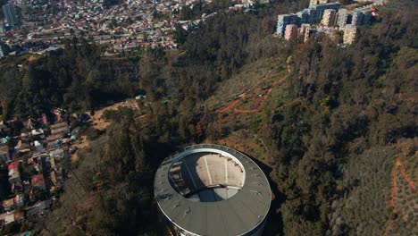 Aerial-dolly-in-of-Quinta-Vergara-Amphitheater,-colorful-buildings-and-autumnal-trees-park-in-Viña-del-Mar-hillside-city,-Chile