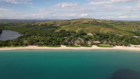Drone-flying-along-the-coastline-of-Natadola-Beach-in-Fiji-looking-at-the-resorts-and-green-mountains